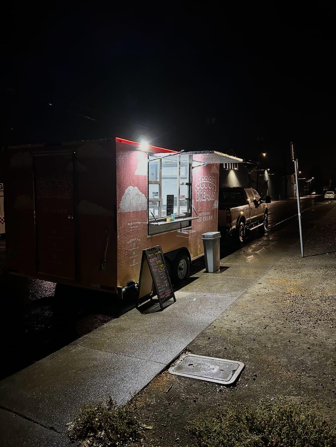 The Scoop Dreams trailer lit up at night serving customers